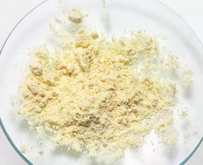 A close-up view of a fine, yellowish powder spread out on a clear glass plate.