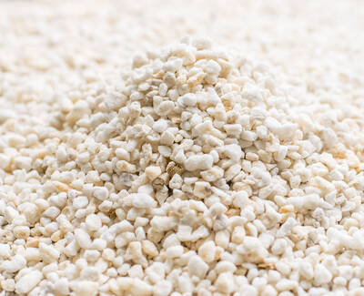 A close-up of a mound of small, white granules on a light surface, resembling aggregate or gravel.