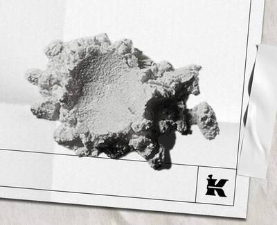 Un fragment de mineral ou de materiau blanc texture, de forme irreguliere, reposant sur un fond clair, avec un petit logo en bas a droite.