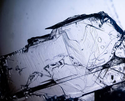 A close-up image of a translucent crystal with intricate internal patterns and textures, illuminated to highlight its clarity and structure.