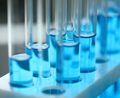 Close-up of test tubes filled with bright blue liquid, arranged in a test tube rack.