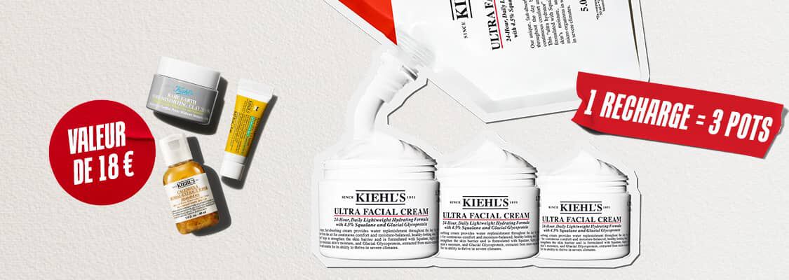 Trois produits de soin pour la peau Kiehl's en format voyage (la creme Ultra Facial Cream, la lotion Calendula Herbal-Extract Toner et le soin contour des yeux Avocado Eye Cream) sont disposes sur un fond blanc texture. Au centre, un cercle rouge peint a la brosse contient l'inscription en blanc "WAARDE VAN €18" (valeur de 18 €).