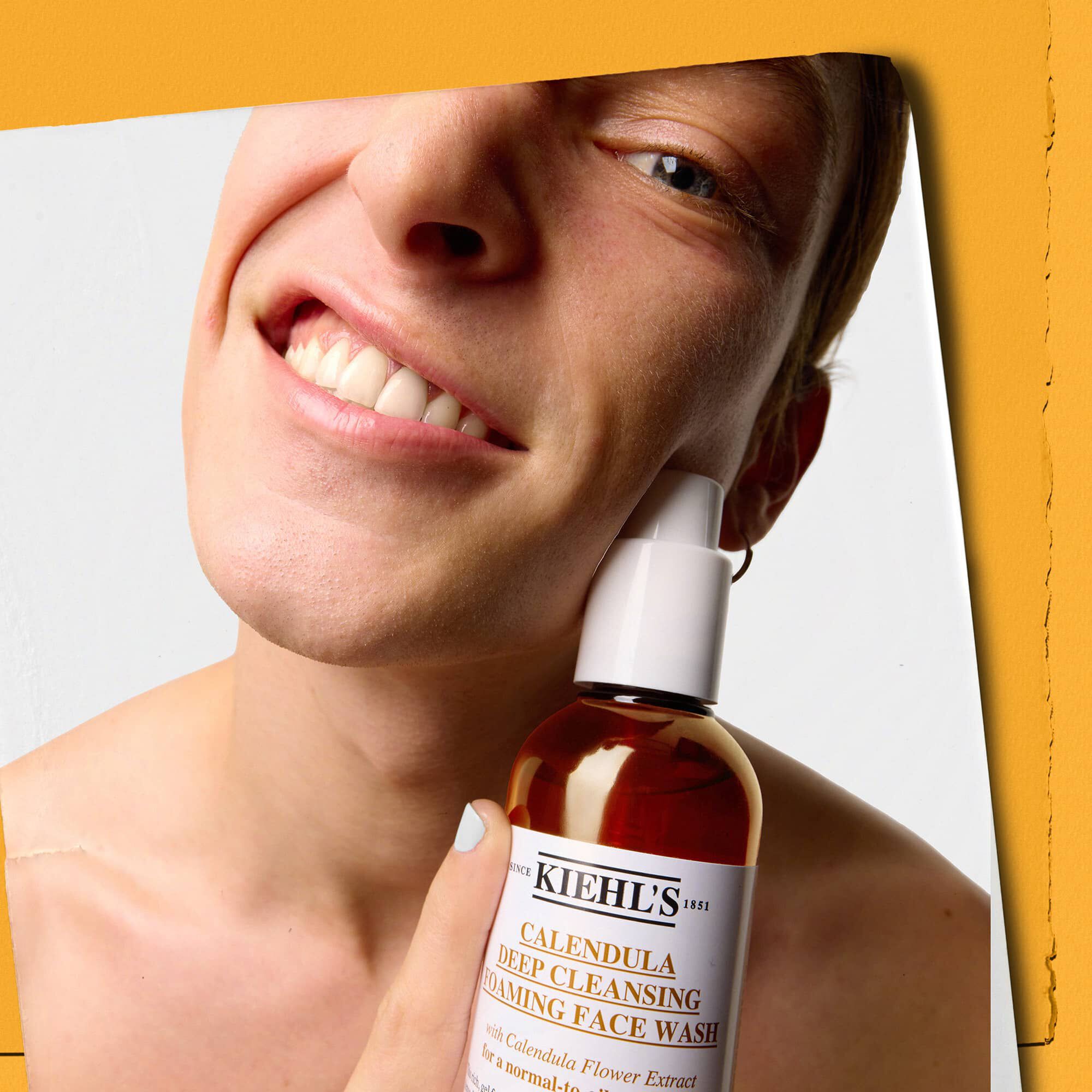Model houdt een fles Kiehl's Calendula Deep Cleaning Foaming Face Wash vast