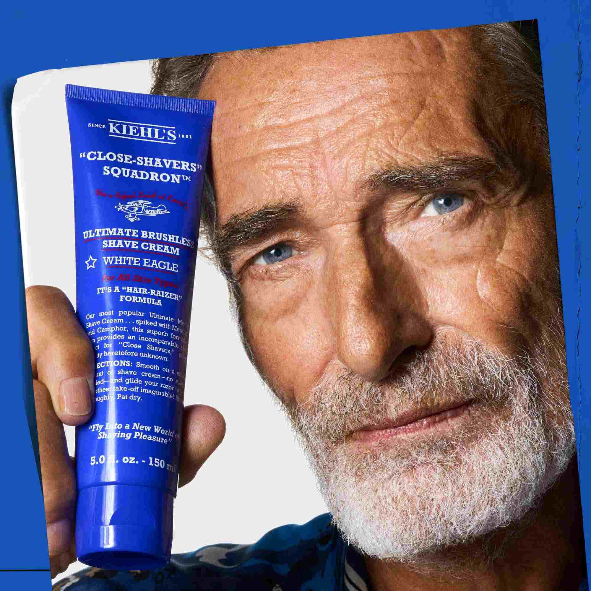 Un homme tenant un tube de Ultimate Brushless Shave Cream White Eagle.