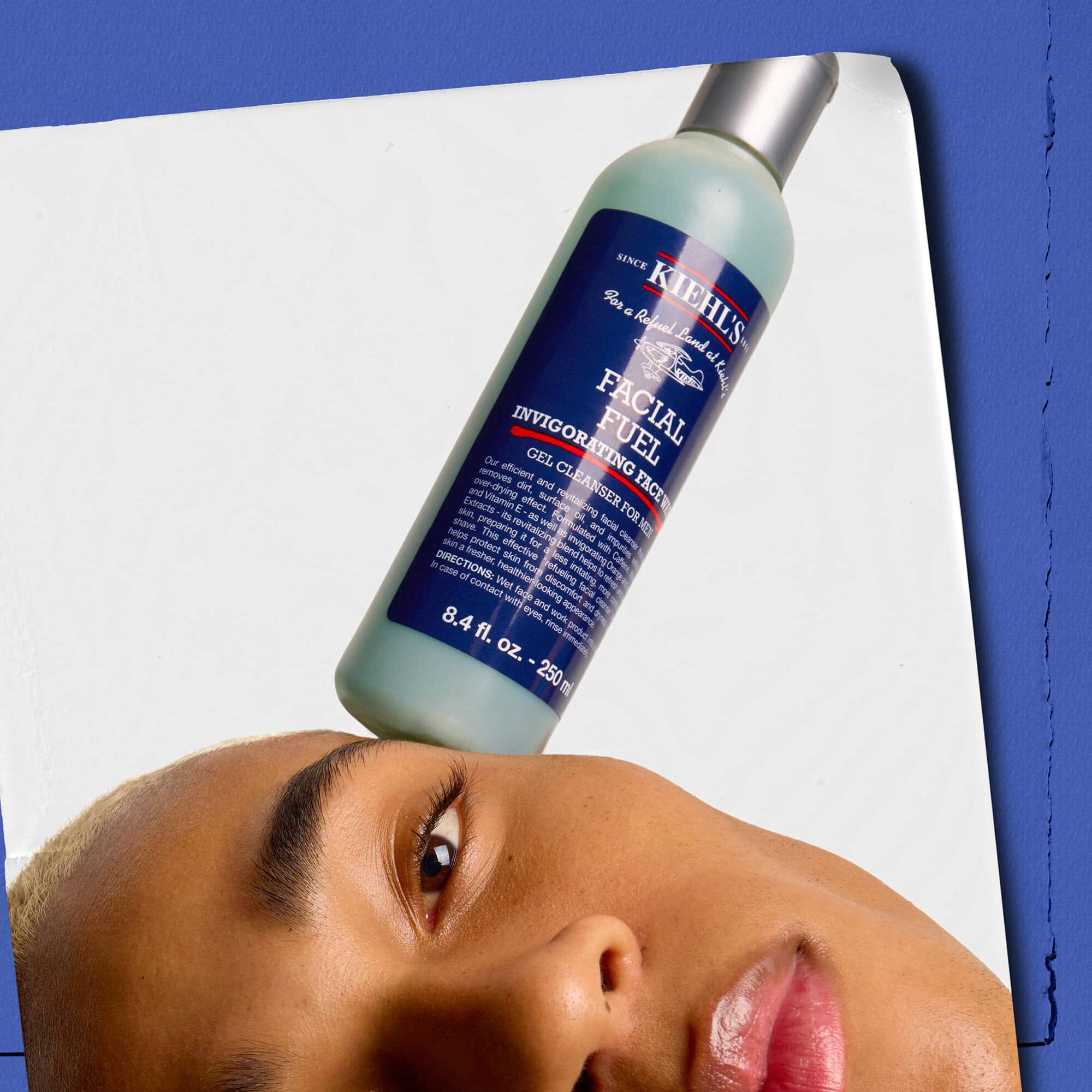 Model met een fles Kiehl's Facial Fuel Energizing Face Wash op het gezicht gebalanceerd