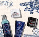 Een promotiebanner van Kiehl's voor Vaderdag. De afbeelding toont vier bestsellers: Facial Fuel gezichtsreiniger, Facial Fuel scrub, Ultra Facial Cream en Age Defender oogcrème. Het ontwerp heeft een vintage thema met illustraties van een vliegtuig, luchtpoststempels en een SHOP NOW knop.